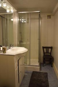 ein Badezimmer mit einem Waschbecken, einer Dusche und einem Stuhl in der Unterkunft Le Jardin Secret in Saint-Antonin