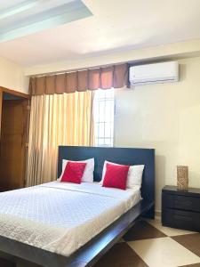 um quarto com uma cama com almofadas vermelhas e brancas em Aparta Hotel Roma em Santo Domingo