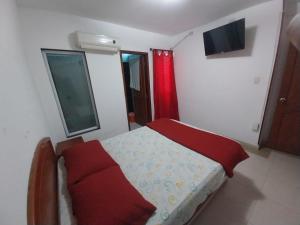 Habitación pequeña con cama con almohadas rojas en HOTEL VIP COMFORT, en Santa Marta