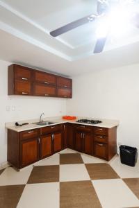 uma cozinha com armários de madeira e uma ventoinha de tecto em Aparta Hotel Roma em Santo Domingo