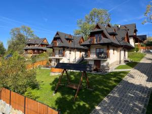 a house with a black roof on a yard at Hole in Zakopane