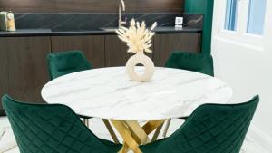 una sala da pranzo con tavolo bianco e sedie verdi di Aries Suite Pompei a Pompei