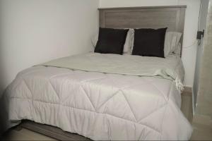 uma cama com lençóis brancos e almofadas pretas em North Breeze Guest House 2 em Toa Baja