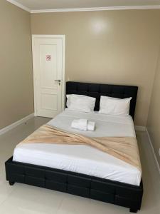 uma cama grande com uma cabeceira preta e almofadas brancas em The Queen em Luanda