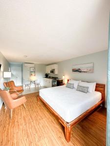 - une chambre avec un grand lit blanc et une chaise dans l'établissement Oasis by the Bay Vacation Suites, à Wasaga Beach