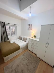a bedroom with a bed and a dresser and a window at Cosy Stunning Flat in London