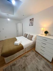 a bedroom with a large bed and a white dresser at Cosy Stunning Flat in London