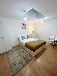 a white bedroom with a large bed and a desk at Cosy Stunning Flat in London