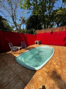 una piscina con 2 sillas y una mesa en Cabañas La Delfina en Puerto Iguazú
