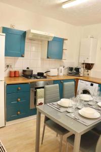 een keuken met blauwe kasten en een tafel met borden erop bij Stunning Guest House FREE WiFi &Parking in Hunslet