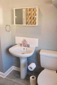 een badkamer met een wastafel, een toilet en een spiegel bij Stunning Guest House FREE WiFi &Parking in Hunslet