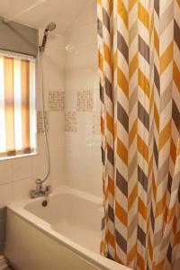 a bathroom with a tub and a shower curtain at Stunning Guest House FREE WiFi &Parking in Hunslet +77 photos