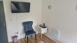 einen blauen Stuhl in einem Zimmer mit einem TV an der Wand in der Unterkunft Dawson House in Darlington