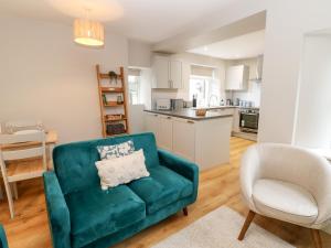 a living room with a green couch and a chair at Hall Garth Cottage in Leyburn