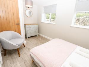 a bedroom with a bed and a chair and window at Hall Garth Cottage in Leyburn