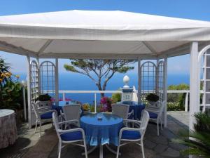 a white tent with blue tables and chairs and the ocean at la guardia in Anacapri