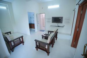 a living room with chairs and a tv and a room at Velvet Vista Premier Service Apartments in Mysore in Mysore