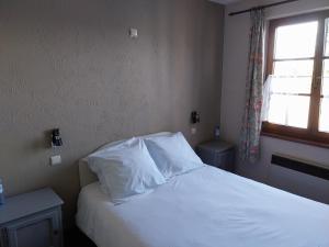 um quarto com uma cama com lençóis brancos e uma janela em Au cœur bion em Bouillon
