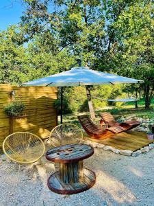 a patio with a table and chairs and an umbrella at Histoire de cru in Saignon