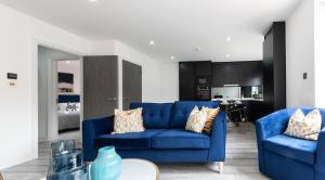 a living room with two blue couches and a kitchen at LUXURIOUS Apartments FREE parking and FREE WiFi! in Staines