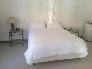 1 dormitorio con 1 cama blanca y 2 mesas en The Landmark Boutique Hotel, en Blantyre