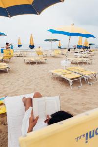 a person laying on a beach reading a book at ANIMA JESOLO - DRAGO VILLAGE, Beach & Pool, 2 Parkings in Lido di Jesolo