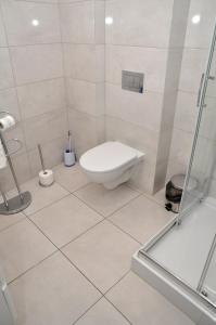 a white bathroom with a toilet and a shower at Pokoje, Apartamenty, Restauracja Marcus in Oborniki