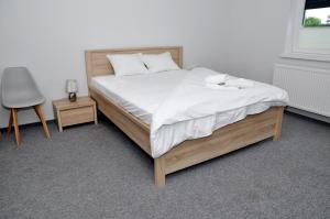 1 dormitorio con 1 cama con sábanas blancas y silla en Pokoje, Apartamenty, Restauracja Marcus en Oborniki