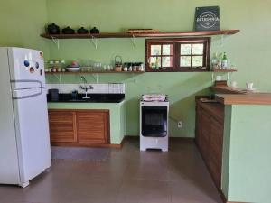 eine Küche mit grünen Wänden und einem weißen Kühlschrank in der Unterkunft Casa de campo com piscina no Vale das Videiras in Petrópolis