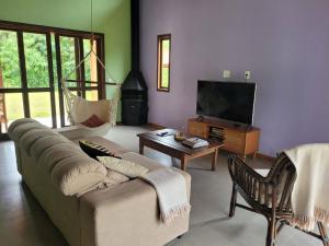 ein Wohnzimmer mit einem Sofa und einem TV in der Unterkunft Casa de campo com piscina no Vale das Videiras in Petrópolis