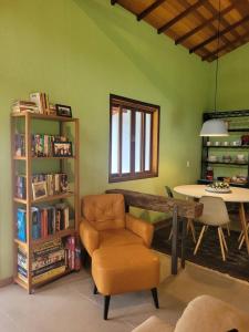 ein Wohnzimmer mit einem Stuhl und einem Tisch mit Büchern in der Unterkunft Casa de campo com piscina no Vale das Videiras in Petrópolis