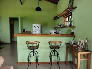 eine Küche mit einer Theke und 2 Barhockern in der Unterkunft Casa de campo com piscina no Vale das Videiras in Petrópolis