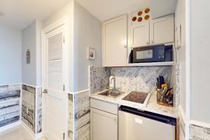 a kitchen with white cabinets and a sink and a microwave at Boardwalk Beach Resort 1900 in Panama City Beach