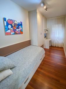 1 dormitorio con 1 cama con una pintura en la pared en Piso nuevo y espacioso en el centro de Mundaka, en Mundaka