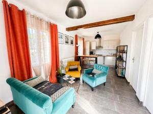 a living room with two blue chairs and orange curtains at Le Tipani in Vernon