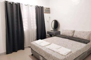 1 dormitorio con cama y cortinas negras en FOMAG House GenSan 2BR en General Santos