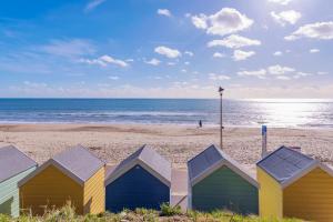 uma fila de coloridas cabanas de praia numa praia em Self-contained flat, off street parking close to town and beach em Bournemouth