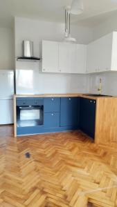 a kitchen with blue and white cabinets and a wooden floor at Urban Nest Apartments Starowiślna 30A in Krakow