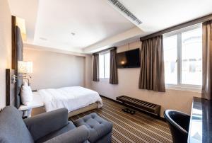 Hub Hotel - Zhongshan Branch في تايبيه: غرفه فندقيه بسرير واريكه