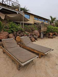two beds sitting on the sand in front of a building at Villas Badiene in Poponguine