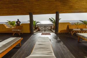 a room with tables and benches and the ocean at Villas Badiene in Poponguine