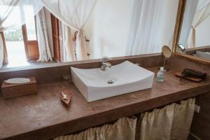 a white sink in a bathroom with a mirror at Villas Badiene in Poponguine