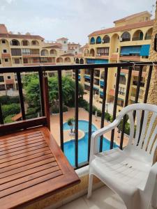 einen Balkon mit einem weißen Stuhl und einem Pool in der Unterkunft Daria in La Mata