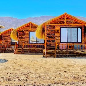 a log cabin with a straw roof on a beach at Magic land taba camp in Taba