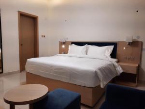 Season Inn Hotel_Bald Sayt في Rustāq: غرفة نوم بسرير ابيض كبير وطاولة