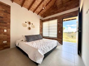 1 dormitorio con cama y ventana grande en Casa Roca con piscina Hospedaje Campestre, en Los Santos