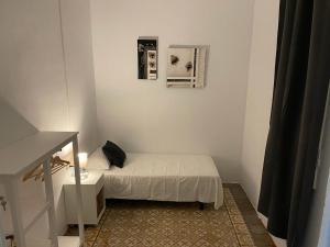 a small white room with a bed and a table at Des Artistes in Barcelona