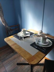 una mesa de madera con dos tazas y platos. en El salto, en Puerto Aysén