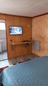1 dormitorio con 1 cama y TV en la pared en El salto, en Puerto Aysén