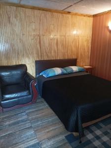 ein Bett und ein Stuhl in einem Zimmer in der Unterkunft El salto in Puerto Aisén
